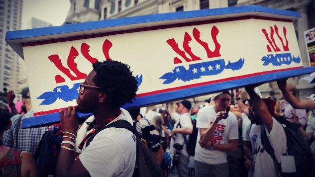 Photo of marchers carrying small coffin, painted on side is upside donkey - symbol of the Democratic Party
