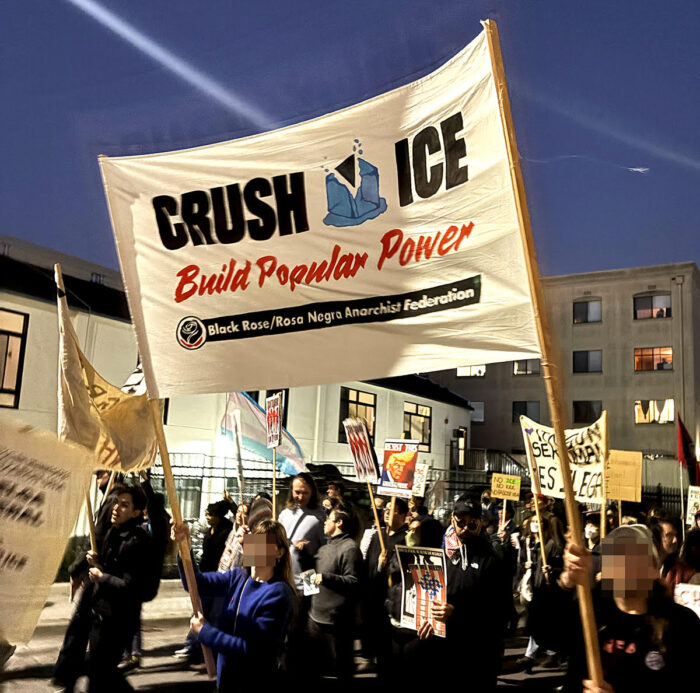 Members hold a banner with "Crush ICE, Build Popular Power" at a evening demonstration.